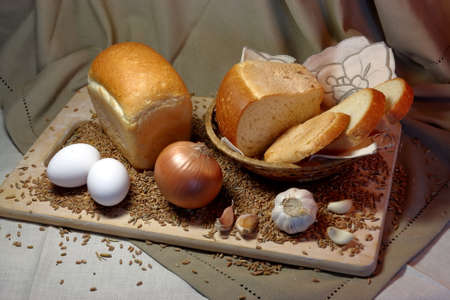 fresh wheat bread on wooden cutting Board basket of straw with eggs garlic wheatの写真素材