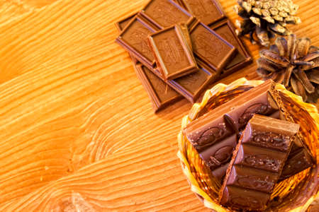 broken lines pieces of milk chocolate on the aged brown wooden background close planの写真素材