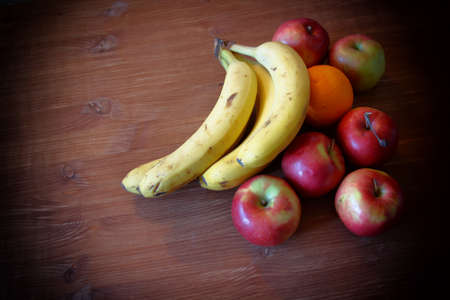 Fruit bananas apples orange on a wooden table backgroundの写真素材