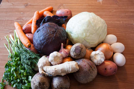 Set of vegetables cabbage potatoes carrots onion garlic parsley dill beet ginger on a wooden table backgroundの写真素材