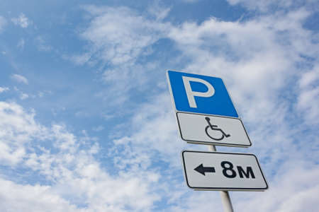 Disabled parking space and wheelchair way sign and symbols on a pole warning motoristsの写真素材