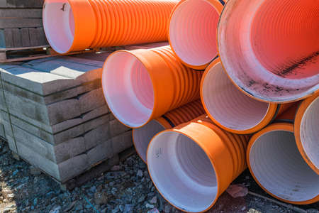 Pipes of PVC large diameter orange color prepared for laying on construction siteの写真素材
