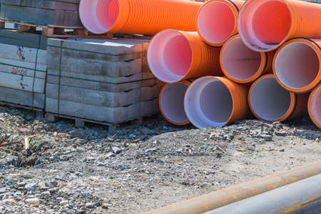 Pipes of PVC large diameter orange color prepared for laying on construction siteの写真素材