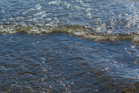 Waves of surf on the shore of the lake sunny summer dayの写真素材