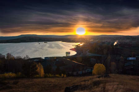 View of the village of Chernoistochinsk Sverdlovsk region from the top of the mountain at sunset in autumnの写真素材