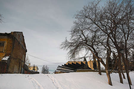 Winter landscape with snowy field, leafless trees and frozen lake in city park.の写真素材