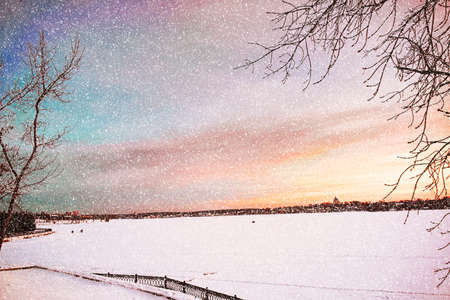 Winter sunset on the shore of the pond in the snowの写真素材