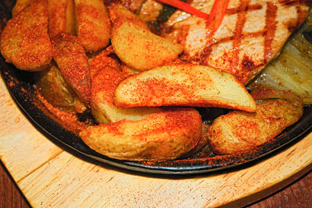 Pork steak with fried potatoes and onions on a cast-iron brazier
