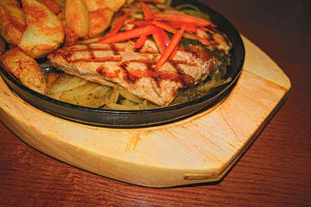 Pork steak with fried potatoes and onions on a cast-iron brazierの写真素材