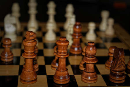 Wooden material chess board and chess pieces in low light with shallow depth of fieldの写真素材