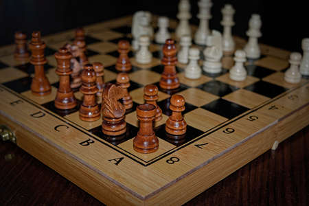 Wooden material chess board and chess pieces in low light with shallow depth of field