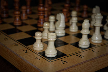 Wooden material chess board and chess pieces in low light with shallow depth of field
