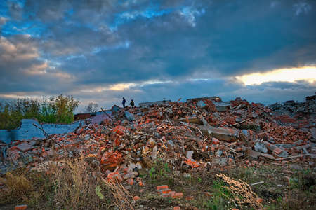 The ruins of a destroyed building in the city against the backdrop of a dramatic autumn sunset skyの写真素材
