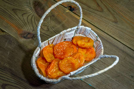 dried apricots in a wicker basket on the background of a wooden table close-upの写真素材