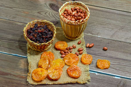 peeled raw peanuts dried apricots raisins on a wooden table background close-up