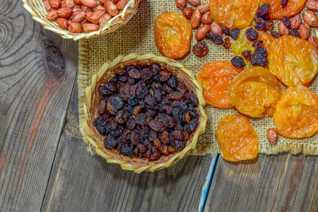 peeled raw peanuts dried apricots raisins on a wooden table background close-up