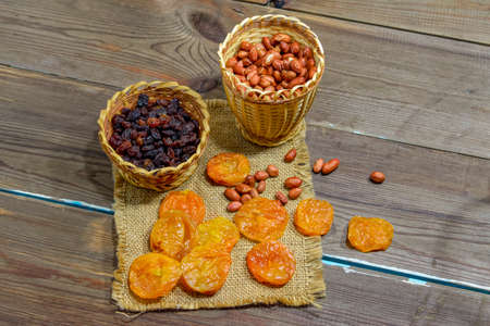 peeled raw peanuts dried apricots raisins on a wooden table background close-upの写真素材