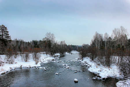 River in winter and tree branches covered with white frost