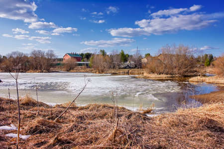 Spring landscape melts ice on a small river at the edge of the village.の写真素材
