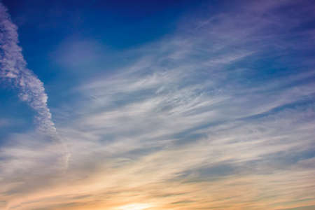 Sky blue and orange light of the sun through the clouds in the skyの写真素材