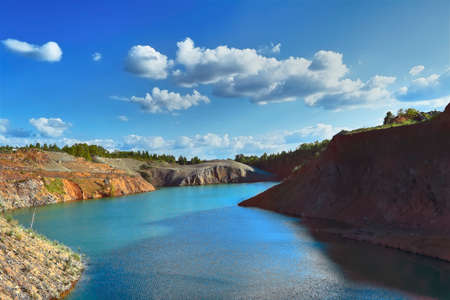 Summer landscape on the shore of a mountain lake against the blue sky and white clouds.の写真素材