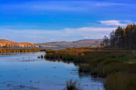Beautiful autumn forest with colorful trees and pacturesque sky reflected in the water. Autumn...