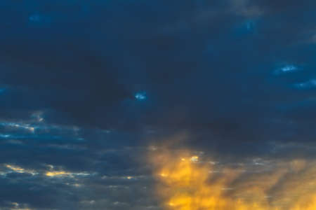 Clouds in the sky are illuminated by the rays of the sun, setting over the horizon