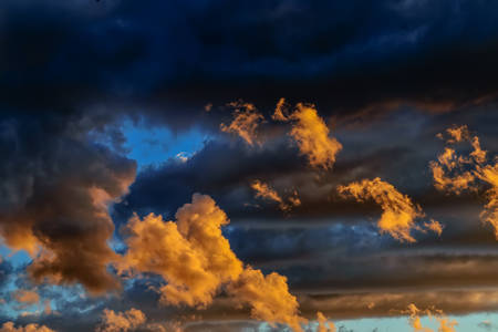 Sky blue and orange light of the sun through the clouds in the skyの写真素材