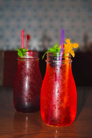 Sweaty bottles of chilled fruit lemonade on a wooden table in a cafe.