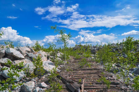 Mountain slope with large stones against a blue summer sky with white cumulus clouds. Large stones on the hill slope.の写真素材