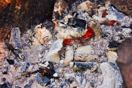 Background of fireplace with gloving embers. Close up view on smouldering fire.