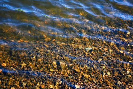 Natural water texture in the summer on a sunny day. Natural ripples on the surface of the river.