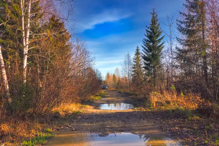 Golden autumn mountain landscape with asphalt road against beautiful clouds sky background. Orange...