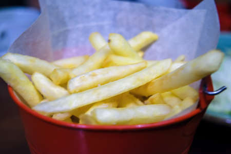 Close-up french fries in a metal bucket on a table.の写真素材