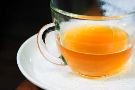 Cup of yellow fruit tea on a wooden table in a cafe.の写真素材