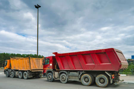 Lorries dump trucks at a construction site are waiting in line for loading.