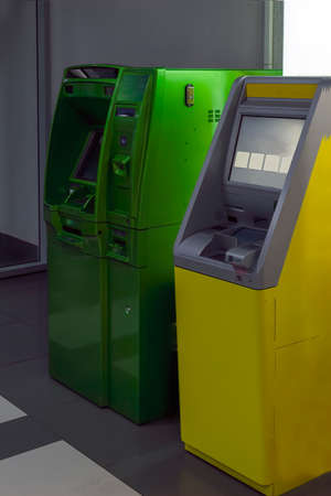 ATM machine. Two yellow and green ATMs in the lobby of the shopping center.