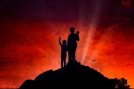 Silhouettes of happy women and girls on the top of the mountain against the backdrop of a dramatic sunset.の写真素材