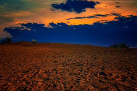 Summer evening sand dune landscape against the backdrop of a colorful sunset.