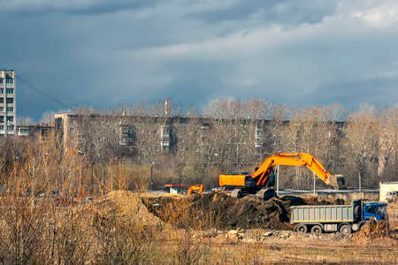Excavator loader machine during earthmoving works outdoors at construction site.