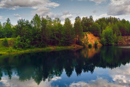 Evening summer landscape on the shore of a forest lake with clear transparent blue water.