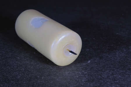 Extinct wax candle on a dark background close-up.
