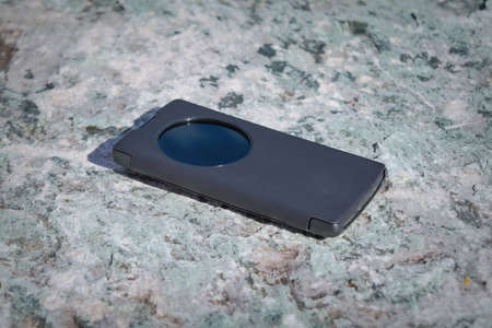 Smartphone in a black case against a background of a stone surface.