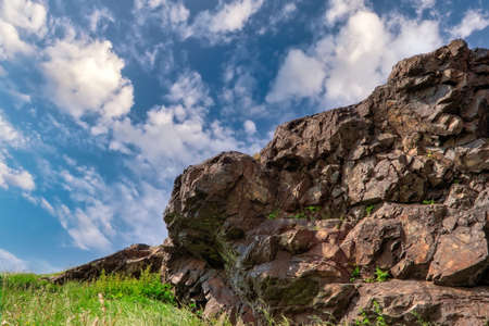 Natural landscape background, bright blue sky with white cumulus cloud. Rock on top of the mountain against the background of a blue summer sky and white cumulus clouds.の写真素材