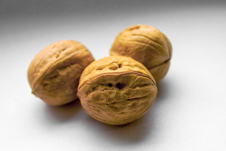 Three walnuts in a shell on a white background close-up.
