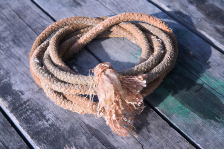 Coil of jute rope on the background of a brown wooden surface close-up.