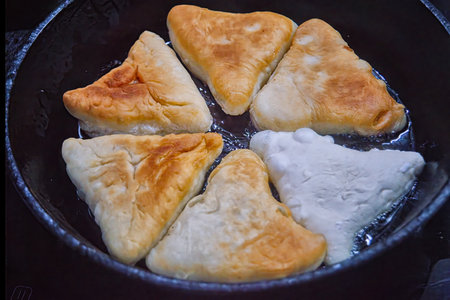 Homemade meat pies are fried in a cast iron frying pan.の写真素材