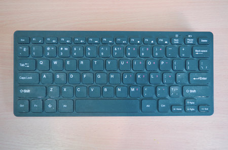 Wireless mini keyboard on a background of a wooden surface.