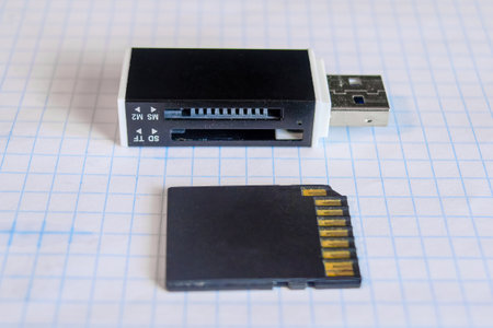 Card reader and flash card against the background of a checkered notebook sheet close-up.