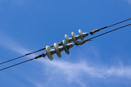 Insulators in overhead power lines against blue sky close-upの写真素材
